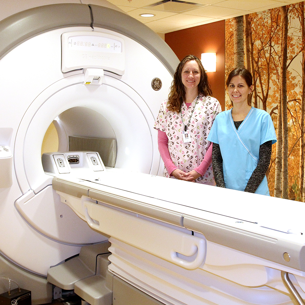 Two employees next to an MRI machine. Beaver Dam Community Hospital medical imaging services