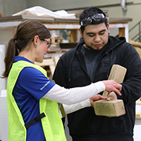 Beaver Dam Community Hospital occupational therapy; therapist works on-site with a factory worker who is holding a pair of wooden blocks.